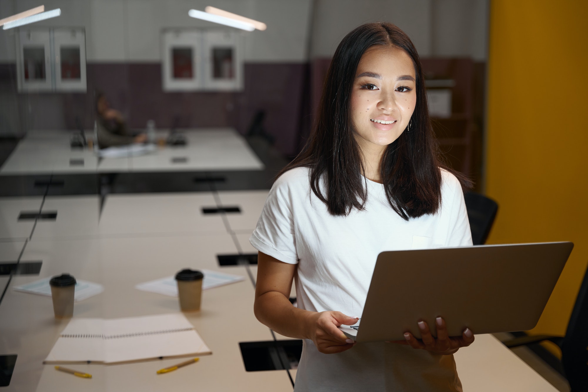 Beautiful smiling office worker with computer in meeting room